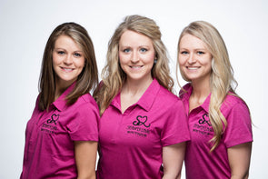 Group photo of three sisters wearing pink polo shirts